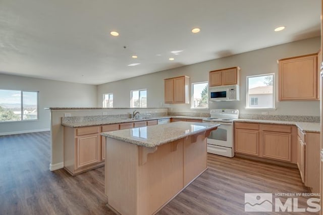 kitchen with sink, white appliances, a breakfast bar, and a kitchen island