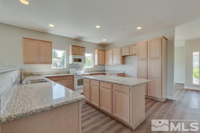 kitchen with white appliances, light stone countertops, sink, and a kitchen island