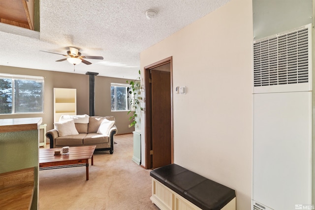 carpeted living room featuring a wood stove, a textured ceiling, and ceiling fan