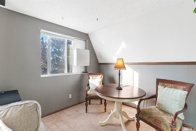 living area featuring lofted ceiling, light colored carpet, and a textured ceiling