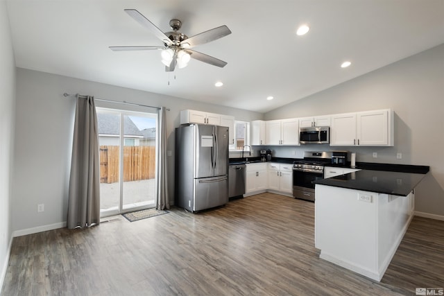 kitchen with dark wood-type flooring, sink, appliances with stainless steel finishes, kitchen peninsula, and white cabinets