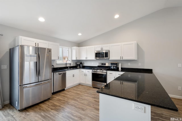 kitchen with sink, white cabinetry, vaulted ceiling, kitchen peninsula, and stainless steel appliances