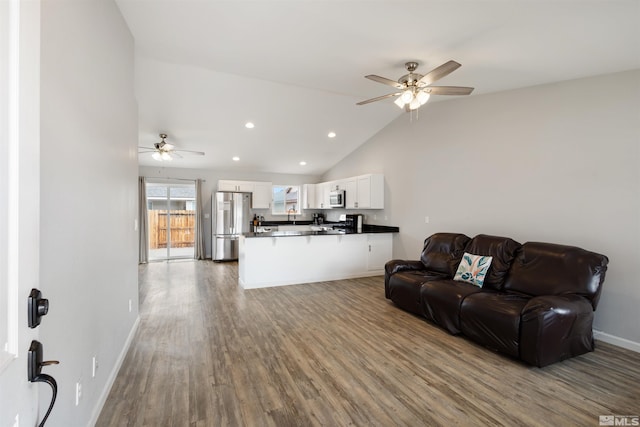 living room with ceiling fan, lofted ceiling, and light hardwood / wood-style floors