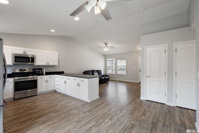 kitchen with vaulted ceiling, appliances with stainless steel finishes, dark hardwood / wood-style floors, white cabinetry, and kitchen peninsula