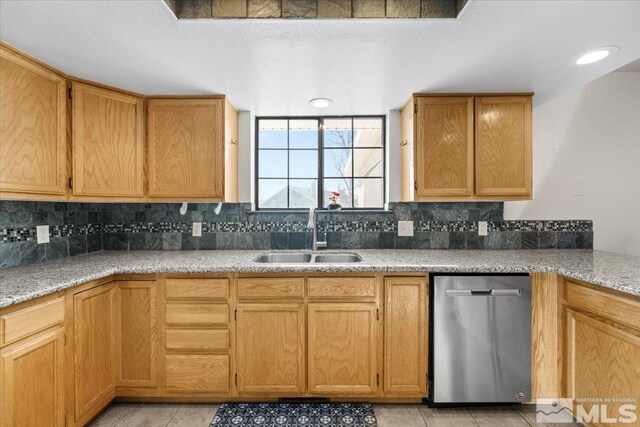 kitchen featuring dishwasher, sink, backsplash, light tile patterned floors, and light stone countertops
