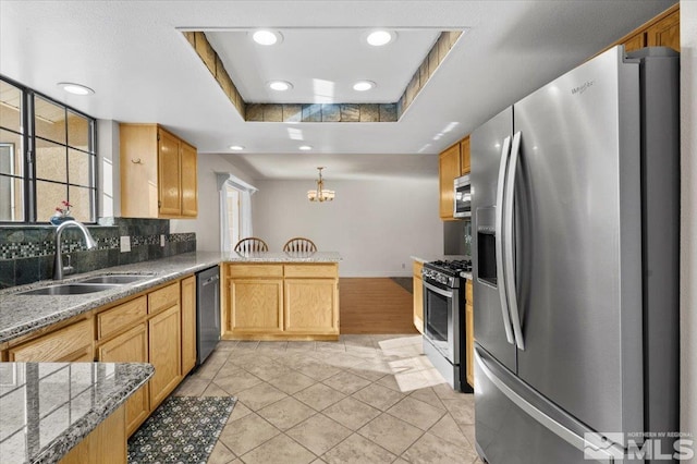 kitchen featuring sink, tasteful backsplash, appliances with stainless steel finishes, a tray ceiling, and kitchen peninsula