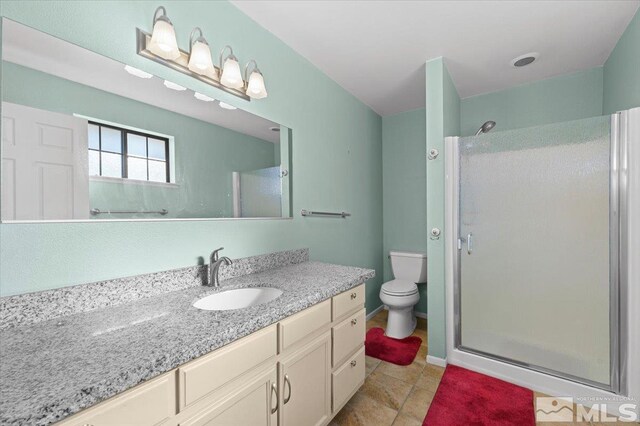 bathroom with vanity, toilet, and a shower with shower door