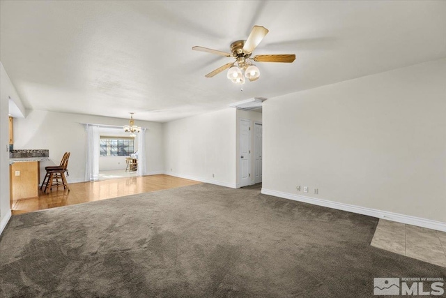 unfurnished living room with carpet floors and ceiling fan with notable chandelier