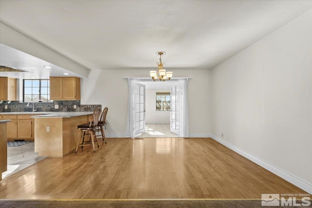 kitchen with plenty of natural light, a kitchen bar, kitchen peninsula, and light hardwood / wood-style floors