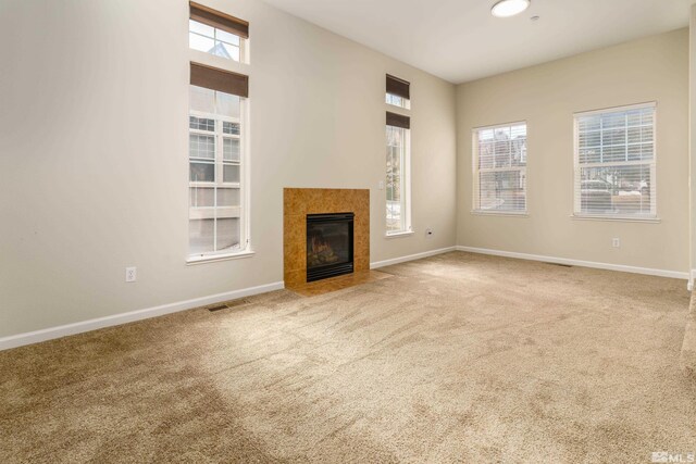 unfurnished living room with a tiled fireplace and carpet