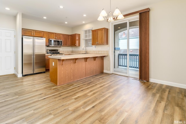 kitchen featuring hanging light fixtures, light wood-type flooring, a kitchen breakfast bar, and appliances with stainless steel finishes