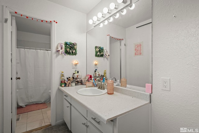 full bath featuring toilet, a textured wall, vanity, and a shower with curtain