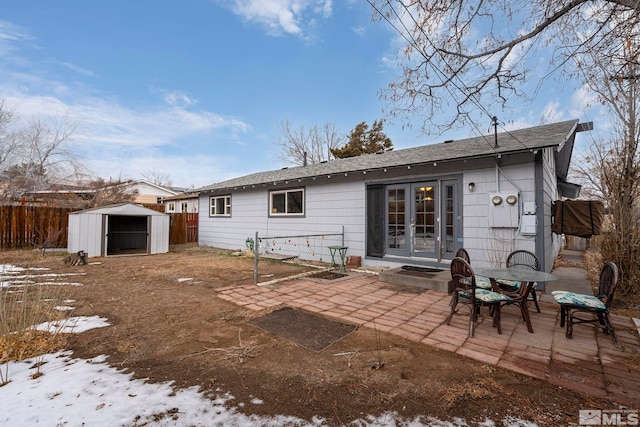 rear view of property featuring an outbuilding, a patio, fence, french doors, and a shed