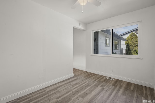 unfurnished room featuring ceiling fan, wood finished floors, visible vents, and baseboards