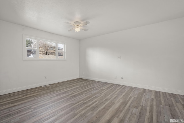 spare room featuring ceiling fan, wood finished floors, visible vents, and baseboards