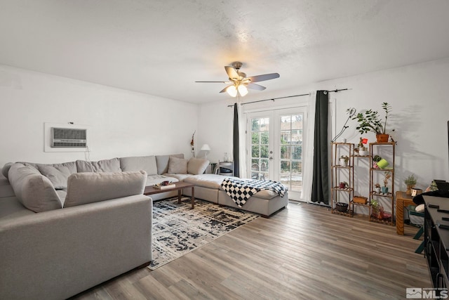 living room with french doors, a wall mounted AC, a ceiling fan, a textured ceiling, and wood finished floors