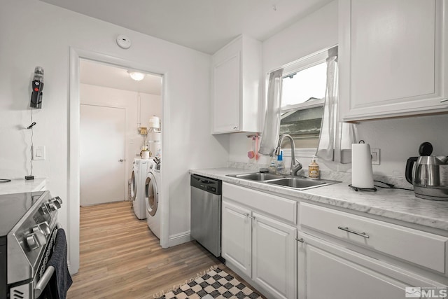 kitchen featuring stainless steel appliances, a sink, white cabinetry, light wood-style floors, and washing machine and clothes dryer