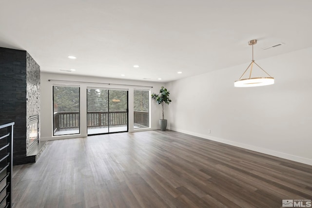 unfurnished living room with a stone fireplace and dark hardwood / wood-style floors