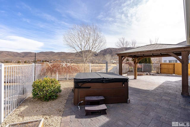 view of patio / terrace with a hot tub, a gazebo, and a mountain view