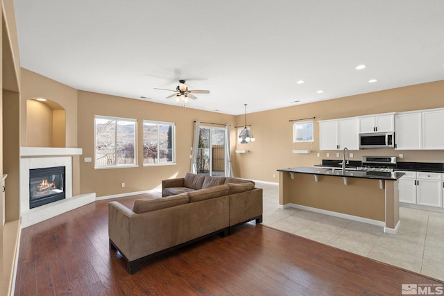 living room featuring sink, ceiling fan, and light hardwood / wood-style flooring