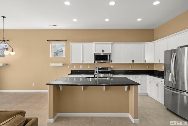 kitchen featuring pendant lighting, sink, stainless steel appliances, a center island with sink, and dark stone counters