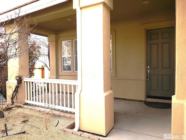 view of exterior entry with a porch and stucco siding