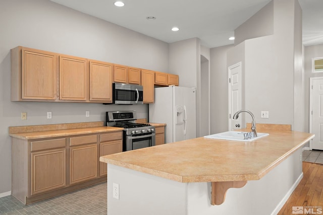 kitchen with sink, stainless steel appliances, a kitchen breakfast bar, light brown cabinetry, and kitchen peninsula