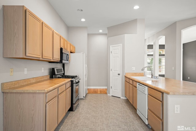 kitchen featuring stainless steel appliances, sink, light brown cabinetry, and kitchen peninsula