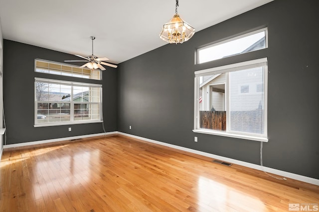 unfurnished room featuring hardwood / wood-style flooring and ceiling fan with notable chandelier