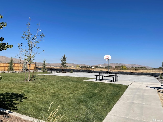 view of community with a mountain view, a yard, and basketball hoop