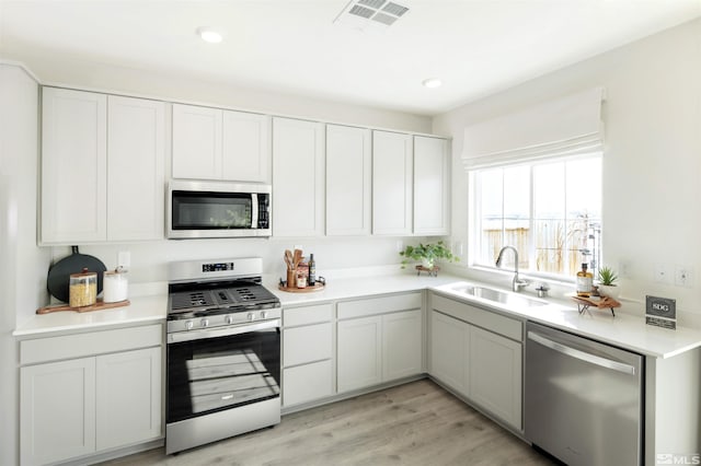 kitchen featuring light wood-type flooring, appliances with stainless steel finishes, sink, and white cabinets