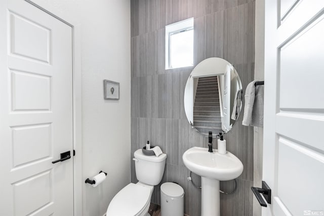 bathroom with toilet and tile walls