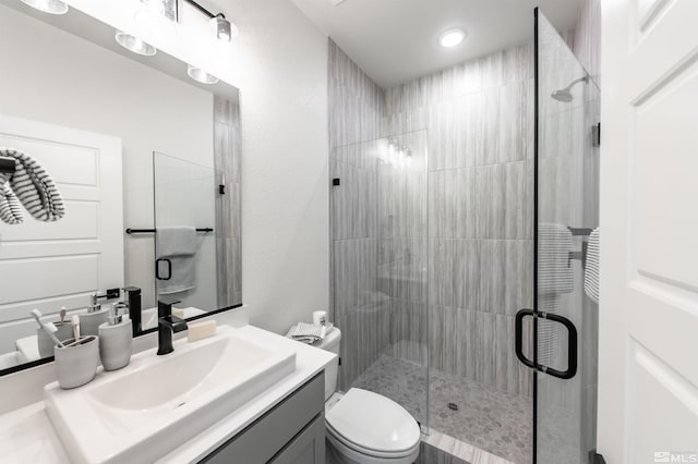 bathroom with vanity, a shower with door, and toilet