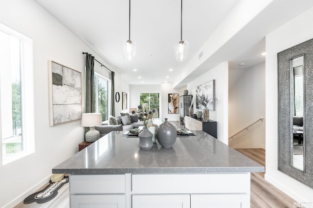 kitchen with dark stone countertops, decorative light fixtures, light hardwood / wood-style flooring, and white cabinets