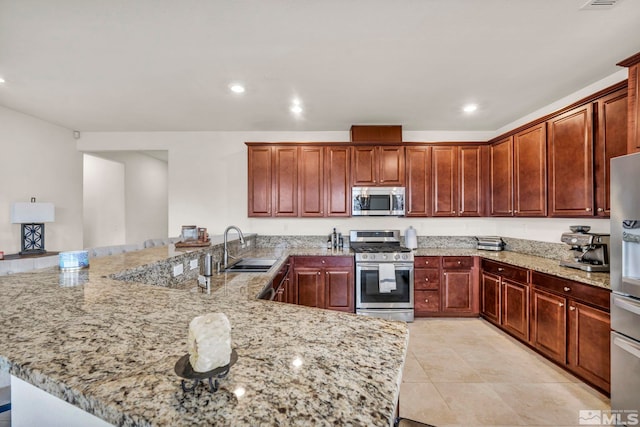 kitchen featuring sink, light tile patterned floors, light stone counters, kitchen peninsula, and stainless steel appliances