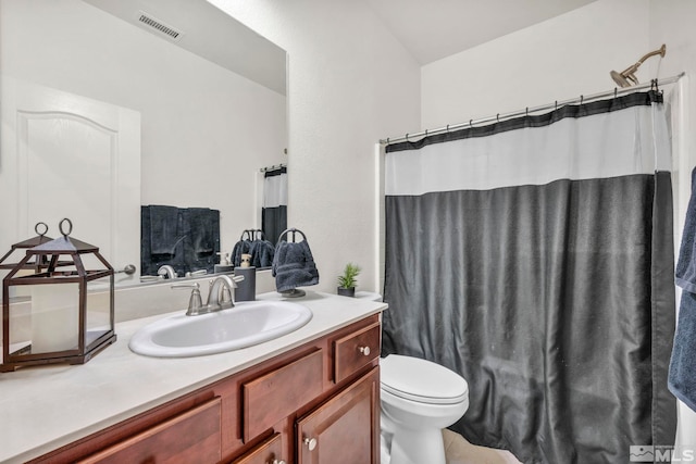 bathroom featuring vanity, walk in shower, and toilet