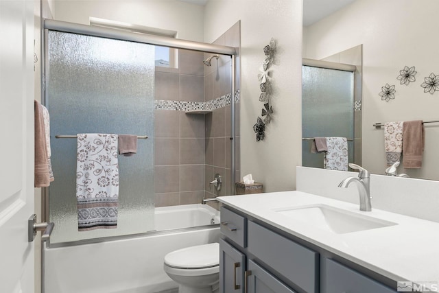 full bathroom featuring vanity, combined bath / shower with glass door, and toilet