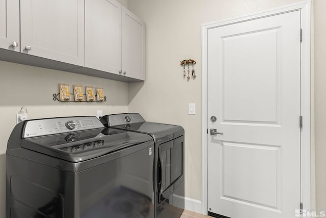 clothes washing area featuring washer and clothes dryer and cabinets