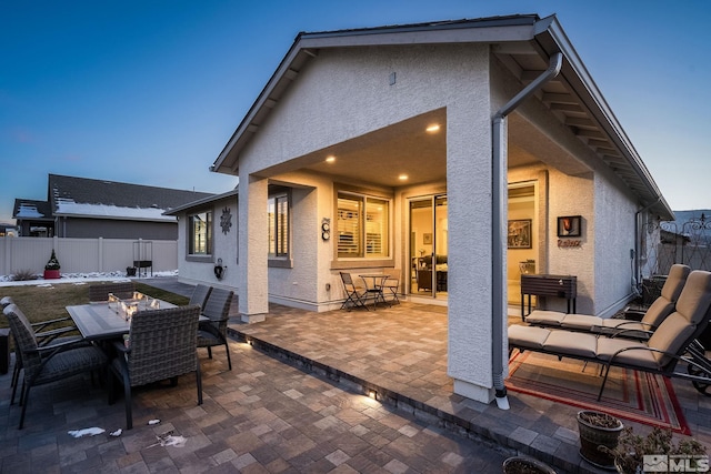 back house at dusk featuring a patio