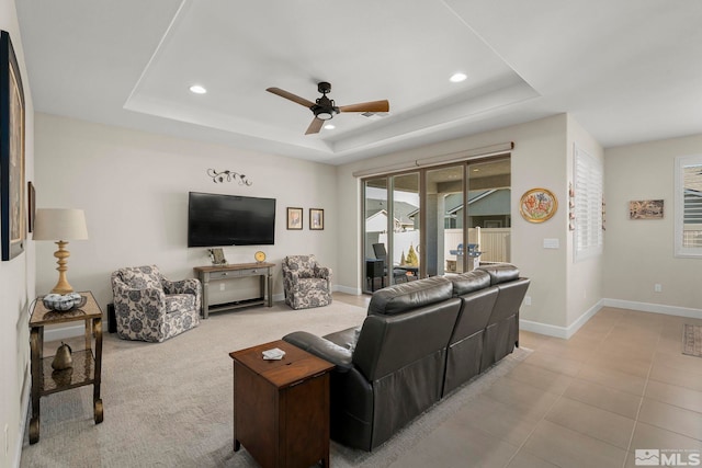 tiled living room featuring ceiling fan and a tray ceiling