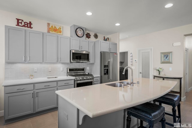 kitchen featuring sink, appliances with stainless steel finishes, a kitchen bar, and a kitchen island with sink