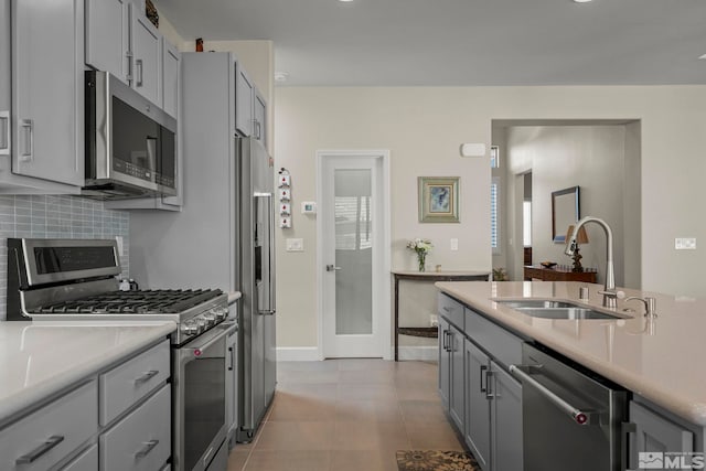 kitchen with gray cabinets, appliances with stainless steel finishes, sink, and decorative backsplash