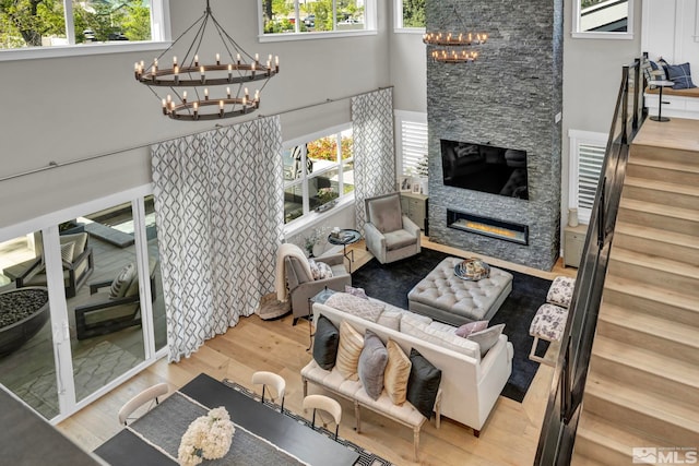 living room featuring a stone fireplace, plenty of natural light, and a chandelier