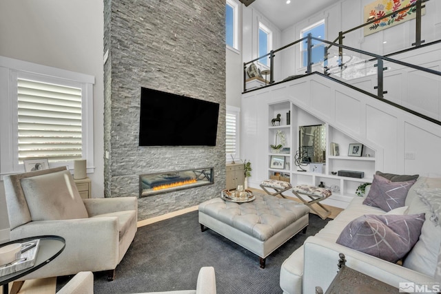 carpeted living room with a high ceiling, plenty of natural light, built in features, and a fireplace