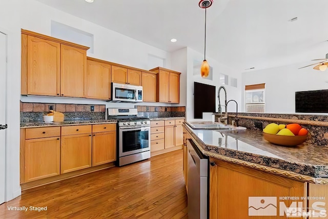 kitchen featuring sink, light hardwood / wood-style flooring, ceiling fan, hanging light fixtures, and stainless steel appliances