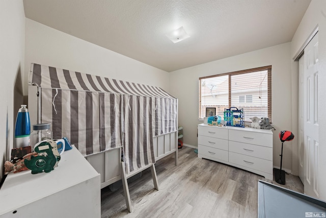 bedroom featuring a textured ceiling and light hardwood / wood-style flooring