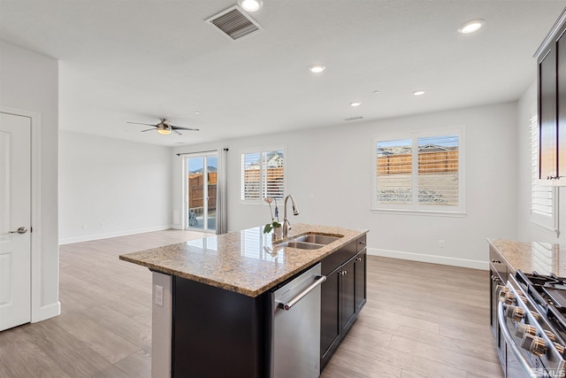 kitchen featuring sink, light stone counters, a center island with sink, light hardwood / wood-style flooring, and stainless steel appliances