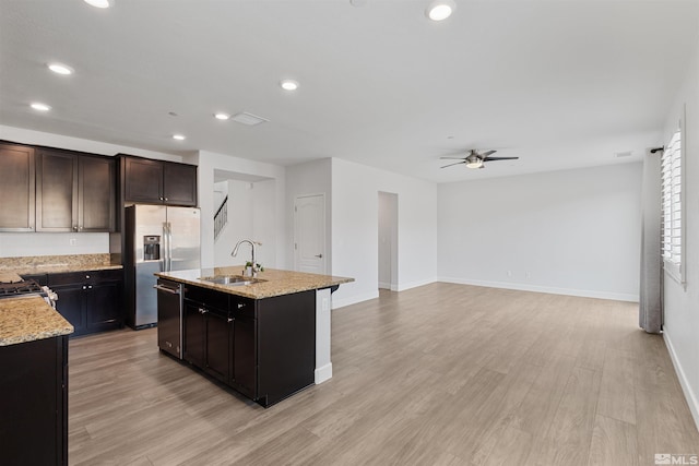 kitchen featuring appliances with stainless steel finishes, light hardwood / wood-style floors, sink, and a center island with sink