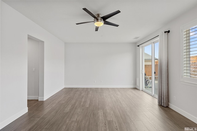 spare room featuring plenty of natural light, dark hardwood / wood-style floors, and ceiling fan