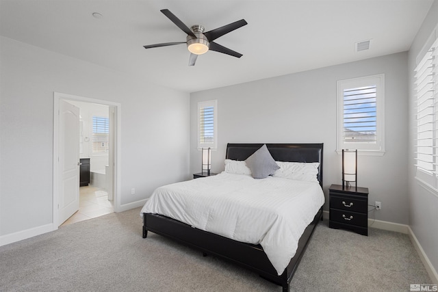 bedroom featuring connected bathroom, light carpet, and ceiling fan